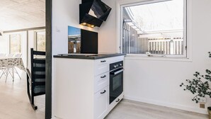 Una cocina moderna con horno integrado, campana extractora negra y ventana con vista a un jardín.