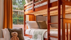 Quarto com beliche, um urso de pelúcia, almofadas e um cobertor.