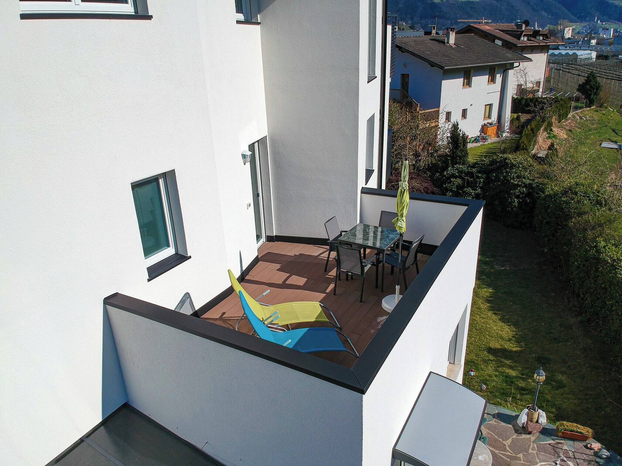A rooftop terrace with a table and chairs, a small play area, and a view of surrounding buildings.