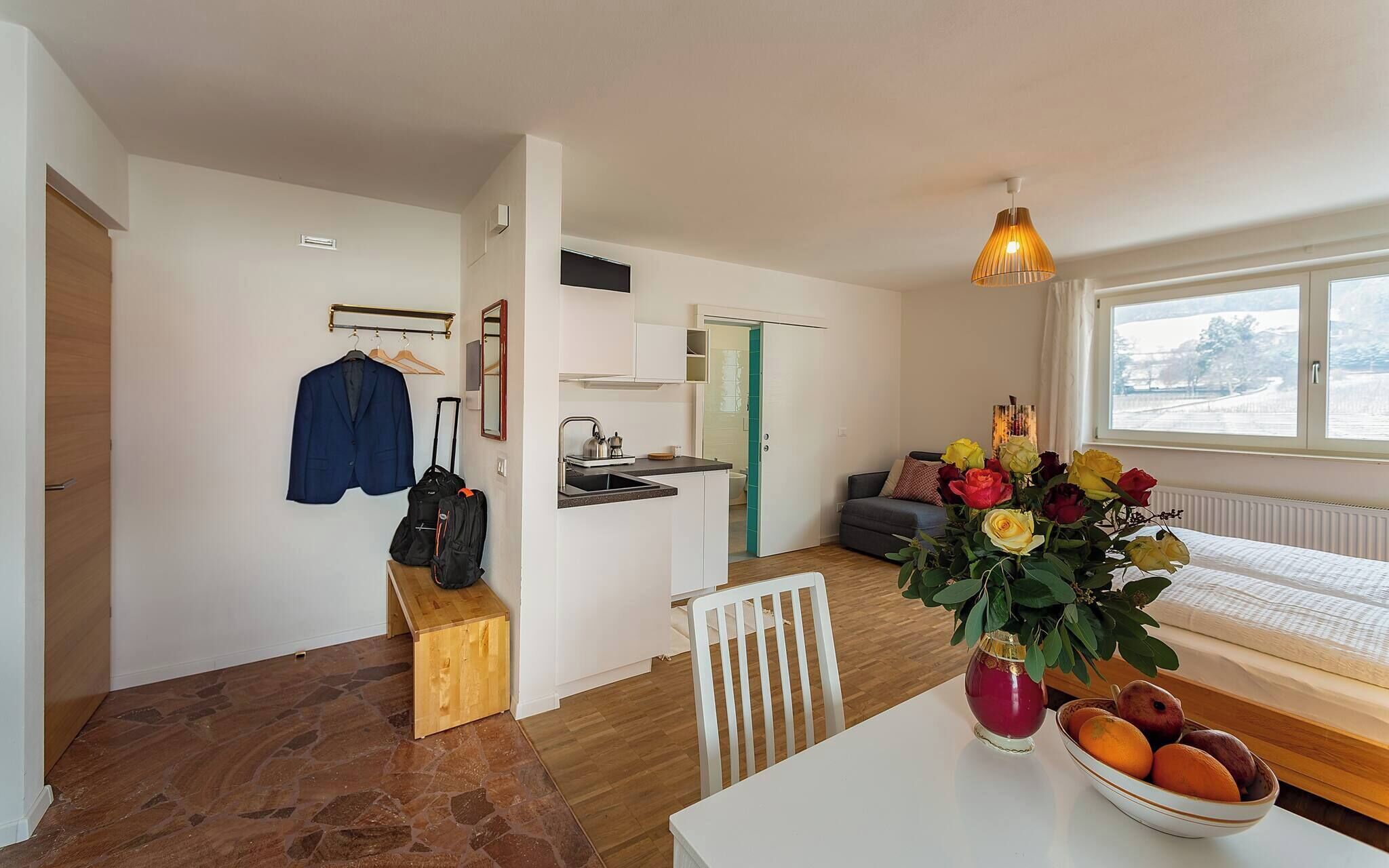 A hotel room with a kitchenette, a dining area, a bed, and a view of a snowy landscape.