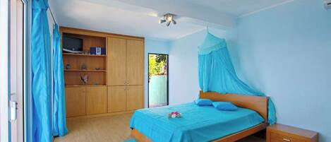 A bedroom with a bed, wooden wardrobe, and a television.