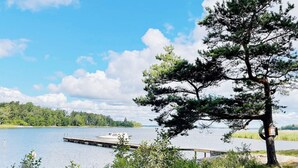 Ein Picknickplatz am Seeufer mit einer Holzbank und einer anlegenden Mole.