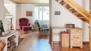 Ein gemütliches Zimmer mit Holzboden, einem roten Sessel, einem Holztisch und einer Treppe.