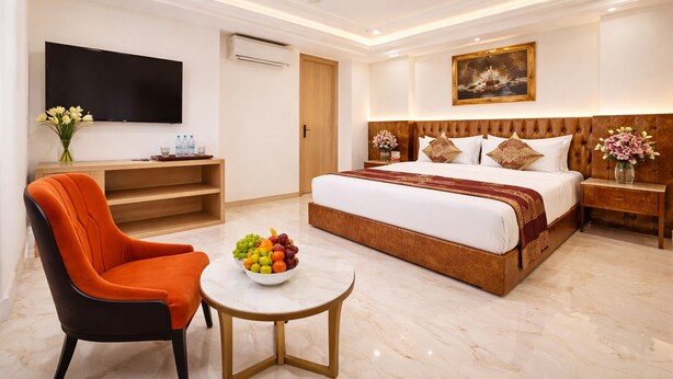 A hotel room with a large bed, a television, a fruit bowl, a chair, and a small table. - HOTEL VENUE Delhi Airport (New Delhi)