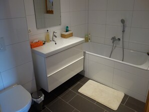 Une salle de bain moderne avec un lavabo blanc, un miroir et une baignoire.