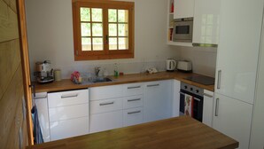 Eine Küche mit weißen Schränken, einer Holzausziehtischplatte, einem Fenster, einer Mikrowelle, einem Toaster und einem Spülbecken.