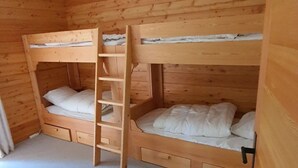 Ein Zimmer mit einem Holzbettgestell mit zwei Betten und einer kleinen Schublade unter dem unteren Bett.