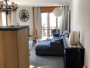 Ein modernes Wohnzimmer mit einer Couch, einem Holzstuhl, einem kleinen Tisch und einer dekorativen Wanduhr.