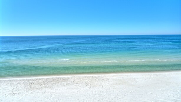 Una playa con aguas azules cristalinas y una orilla arenosa.