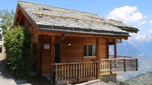 A wooden cabin with a stone roof, a balcony, and a mountain view. - Chalet Nestled in Mountains and Garden (Nendaz)