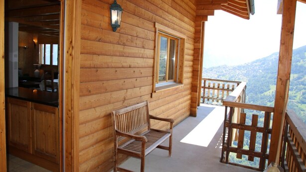 A wooden cabin with a balcony, a bench, and a broom. - Chalet Nestled in Mountains and Garden (Nendaz)