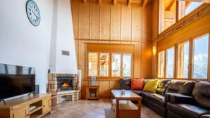 A cozy living room with a fireplace, wooden walls, a television, and a leather sofa. - Chalet Nestled in Mountains and Garden (Nendaz)