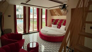 A bedroom with a large bed, a red sofa, a small table, and a wooden staircase. - Royal Shangrila Balakot (Balakot)