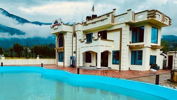 A large, multi-story building with a swimming pool in front. - Royal Shangrila Balakot (Balakot)