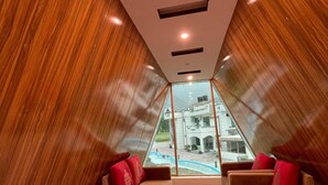 A modern interior with a sloped ceiling, wooden paneling, and two sofas with red cushions. - Royal Shangrila Balakot (Balakot)