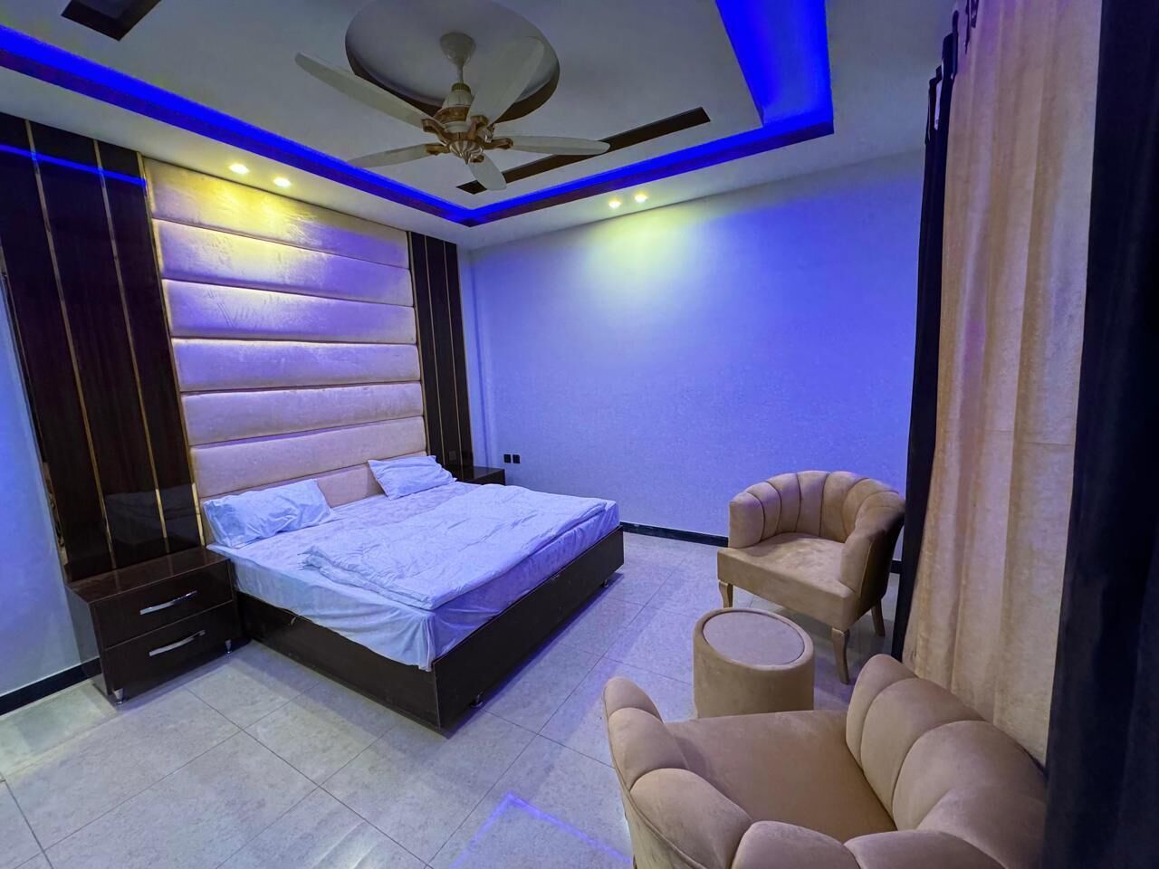 Een moderne slaapkamer met een bed, een plafondventilator en een zithoek.