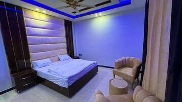 Een moderne slaapkamer met een bed, een plafondventilator en een zithoek.