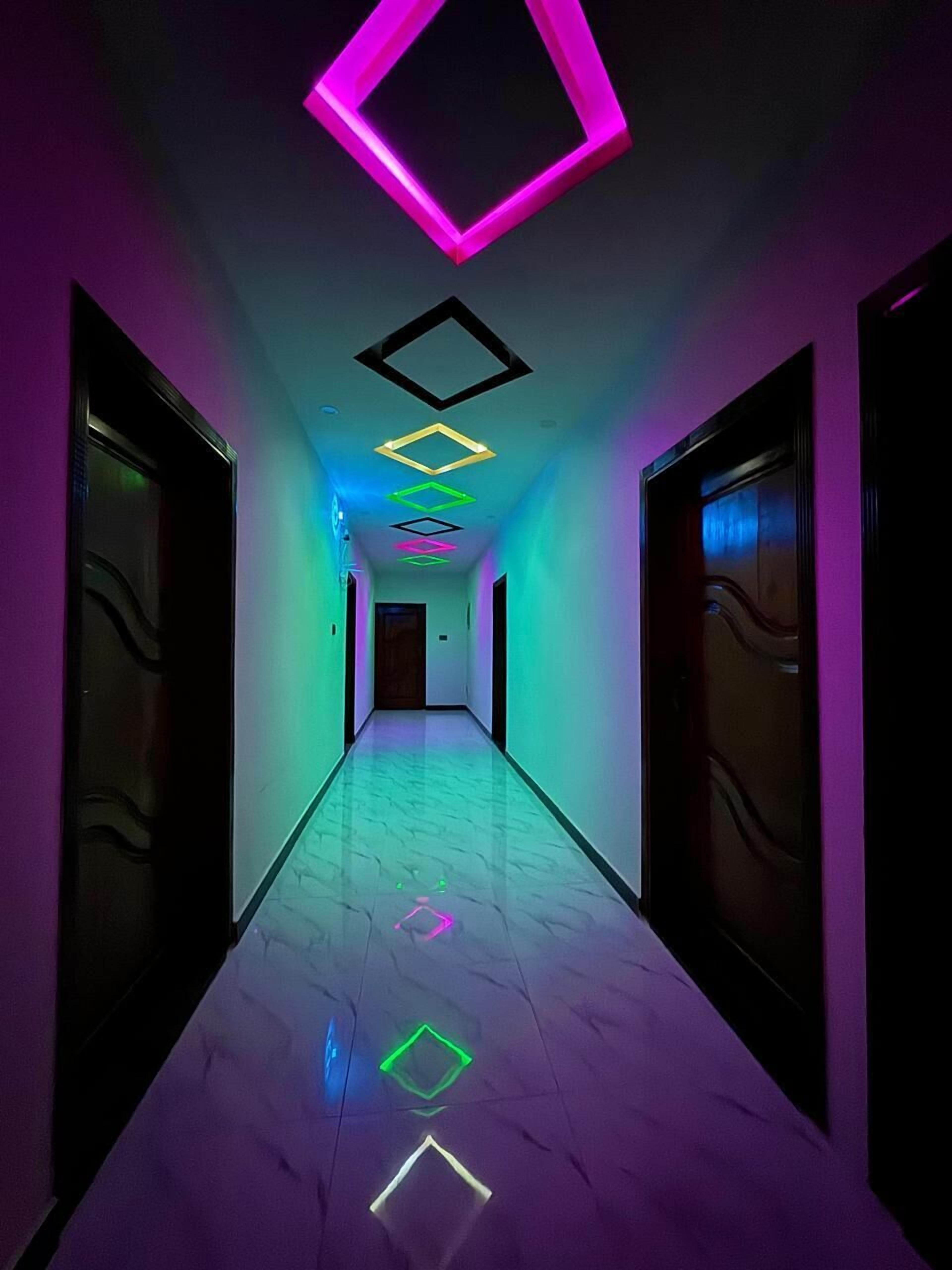 Un pasillo con suelo y paredes reflectantes, que conduce a una puerta al final.