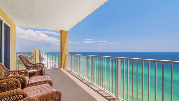 A balcony with wicker furniture and a view of the ocean.