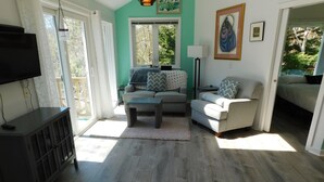 A living room with a sofa, a coffee table, a TV, and a lamp. - Bright and cozy private cottage (CS0037) (Wellfleet)