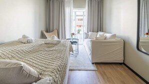 Une chambre d’hôtel avec un lit, un canapé, une petite table et un miroir.