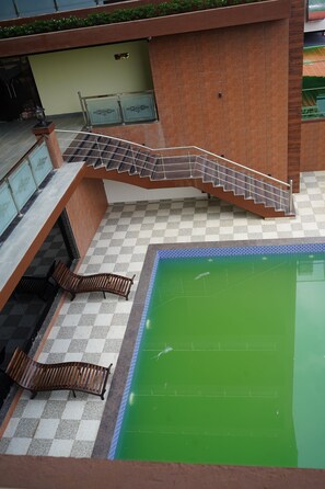 A pool area with a checkered floor, a wooden bench, a staircase, and a railing. - SN Blue Hotel (Alto de Porvorim)