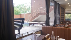 Un coin repas avec une table dressée pour deux personnes, un escalier et une vue sur des palmiers.