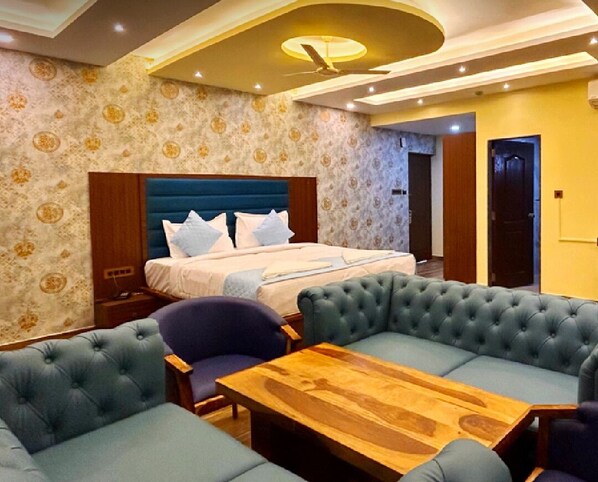 Una habitación de hotel con una cama grande, una mesita de centro de madera y una zona de estar con sofás.