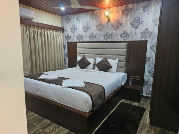 Una cama bien hecha con cabecera, una mesita de noche y una lámpara de pared.