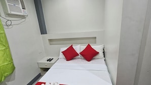 Una habitación de hotel con cama, mesita de noche, aire acondicionado instalado en la pared y cortina verde.