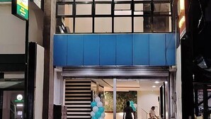 Una entrada de edificio con una escalera que conduce a un segundo piso, un cartel y una persona caminando adentro.