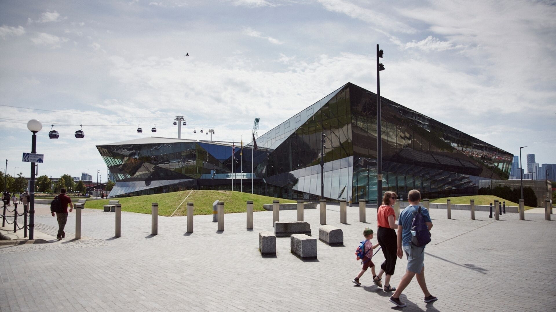 A modern building with a glass facade, a paved walkway, and a few people walking.