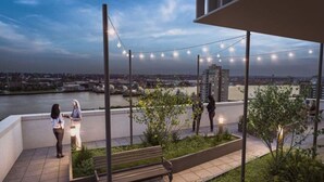 An outdoor terrace with a river view, string lights, and a bench. - -15% LUX Riverside Duplex Masionette By LCY/ExCeL I 25min to Tower of London (London)