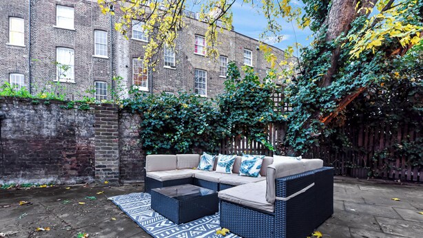 A patio area with a sofa set, a coffee table, and a patterned rug.