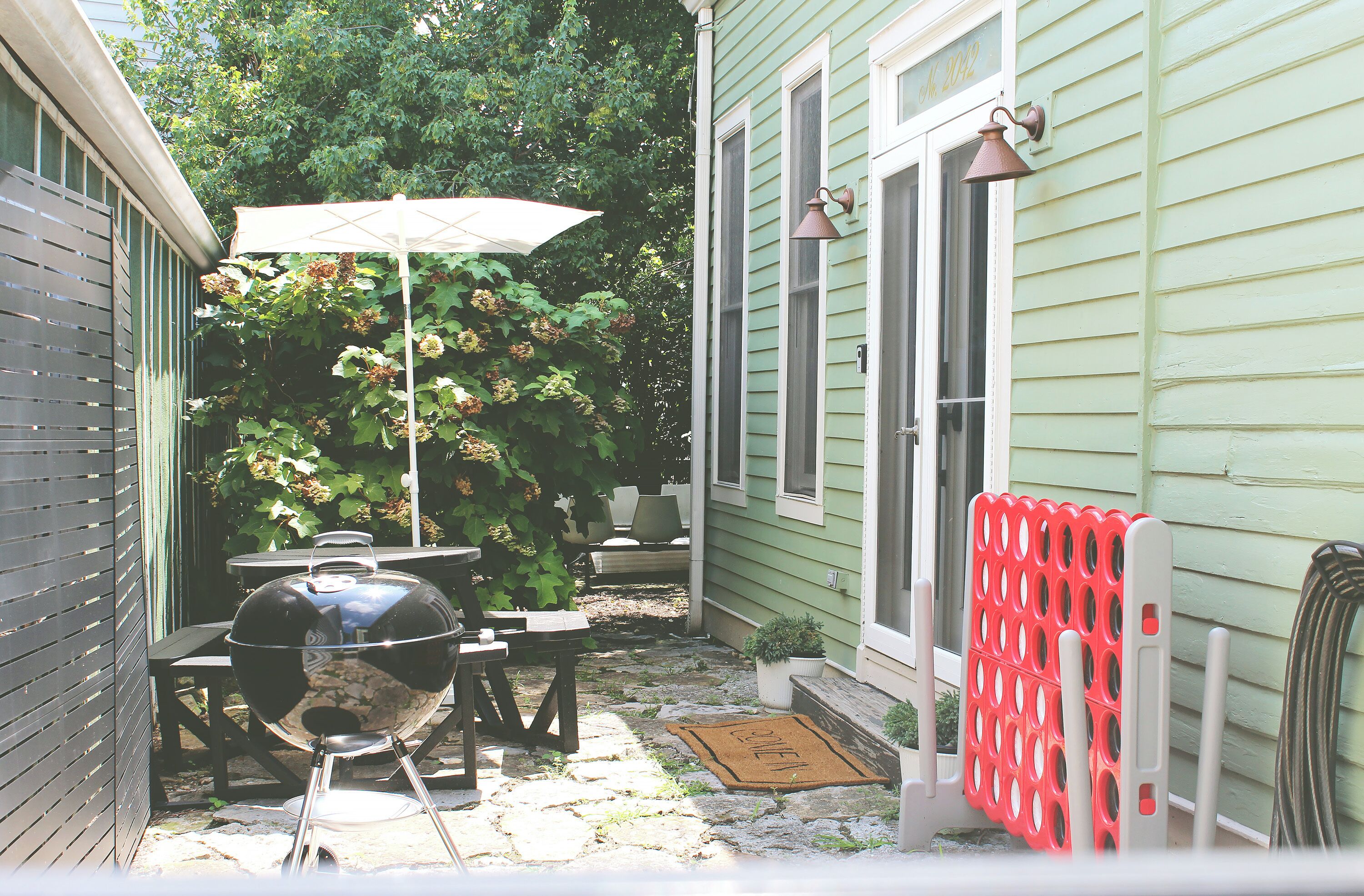 En terrasse med grill, udendørs bord og parasol.