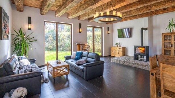 A spacious living room with a fireplace, dark tiled flooring, and a high wooden ceiling. - Beautiful Villa With Spacious Rooms (Lešany)