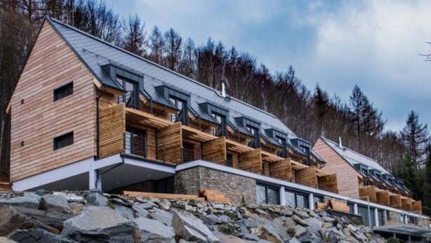 A modern wooden cabin with multiple balconies, set against a rocky hillside and surrounded by trees. - Tranquil Villa With Nature Access (Mala Moravka)