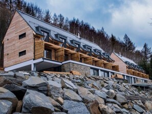 A modern wooden cabin with multiple balconies, set against a rocky hillside and surrounded by trees. - Tranquil Villa With Nature Access (Mala Moravka)
