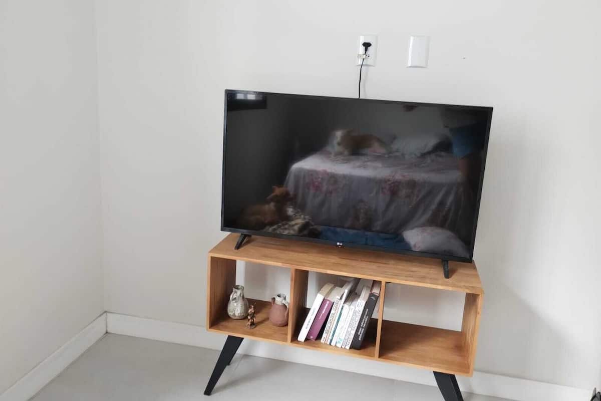 A television on a wooden stand with a shelf below.