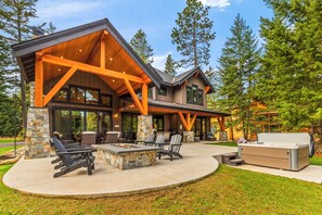 A modern house with a covered patio, stone pillars, and a large outdoor seating area.