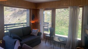 A cozy room with a wooden interior, a sofa, a small table, and a TV. - Classy Apartment Amid Hills (Veysonnaz)