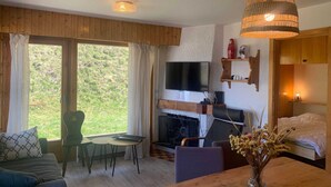 A cozy living room with a fireplace, a TV, and a dining area. - Classy Apartment Amid Hills (Veysonnaz)