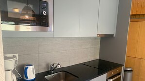 A modern kitchen with a black countertop, stainless steel sink, and a kettle. - Classy Apartment Amid Hills (Veysonnaz)