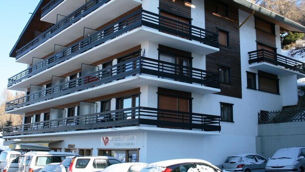 A multi-story building with balconies, a sign for 'Bureau de Vente', and parked cars. - Classy Apartment Amid Hills (Veysonnaz)
