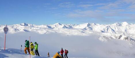 Un paysage de montagne enneigé avec un groupe de personnes sur une piste de ski.