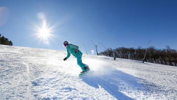 Een snowboarder op een besneeuwde helling met een heldere lucht.
