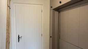 Een hal met een witte deur, houten ski's die tegen de muur leunen en een schuifdeurkast.