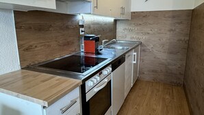 Een compacte keuken met een ingebouwde oven, een kookplaat en een spoelbak.