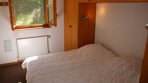 A bedroom with a bed, a window, a radiator, and a wooden door. - Stunning Apartment With Mountain Views (Veysonnaz)