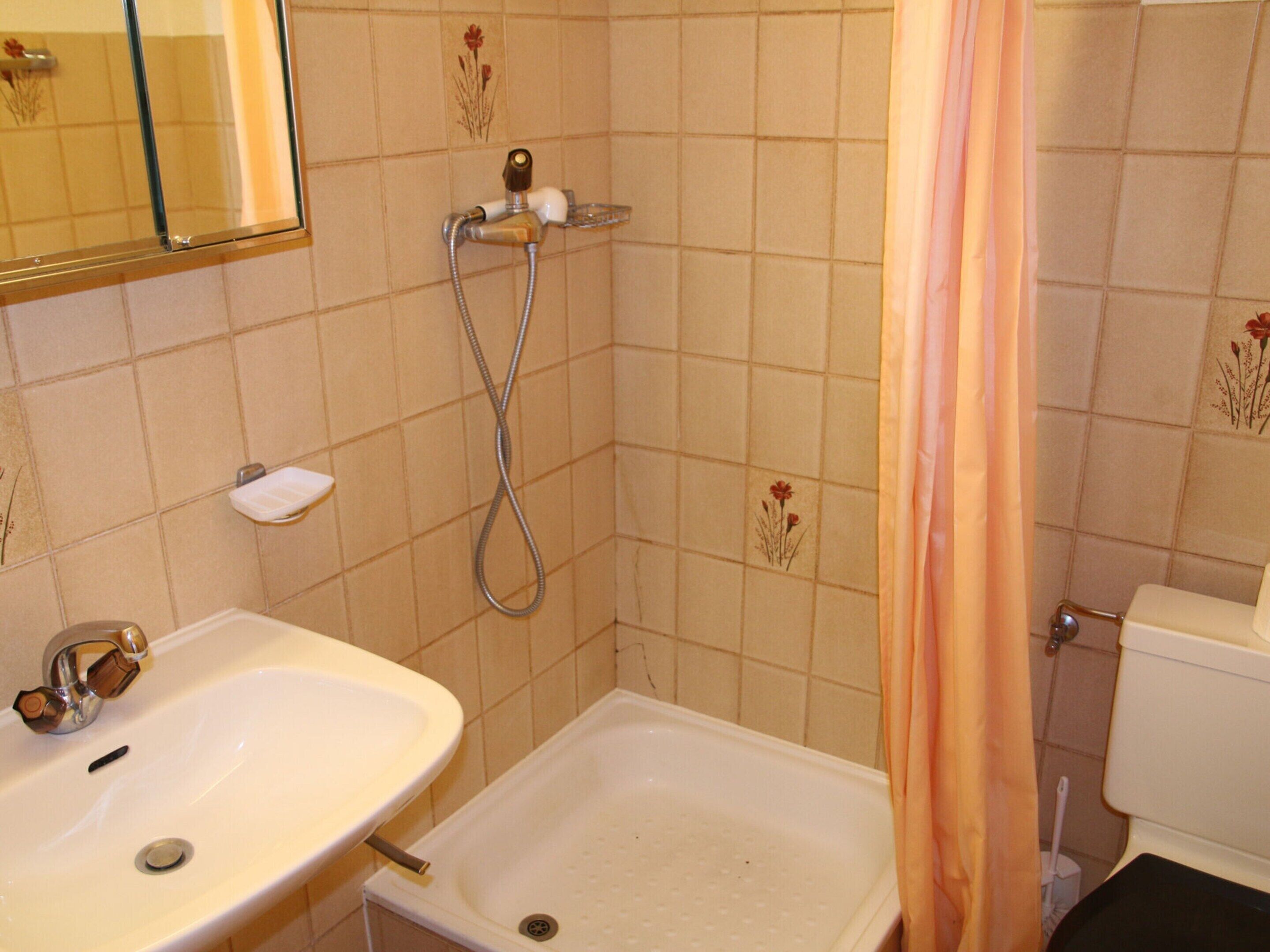A bathroom with a sink, shower, and toilet.
